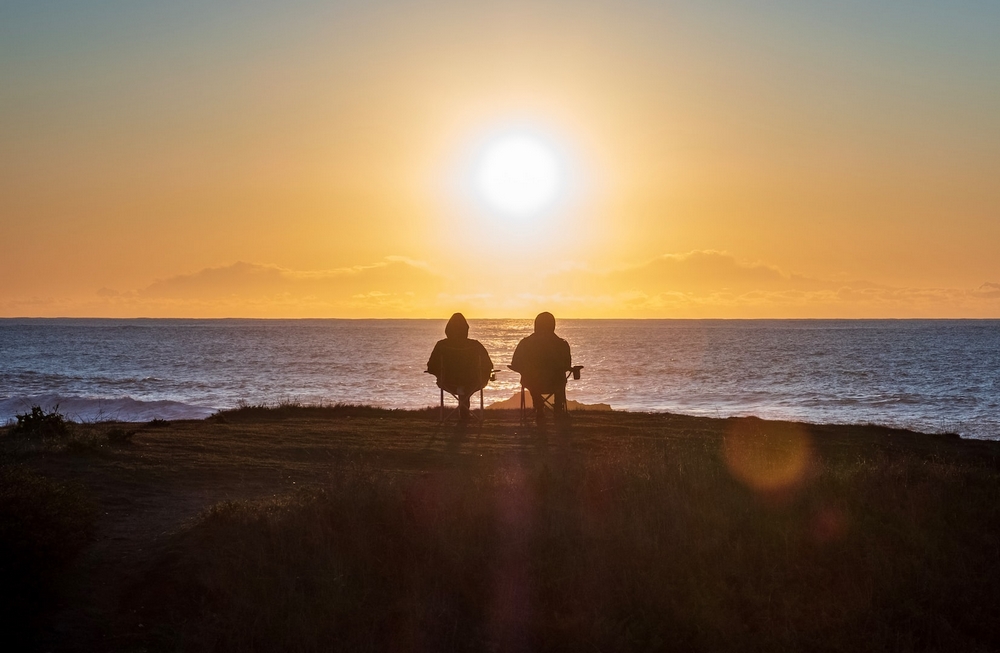 2 personnes devant la mer et le soleil